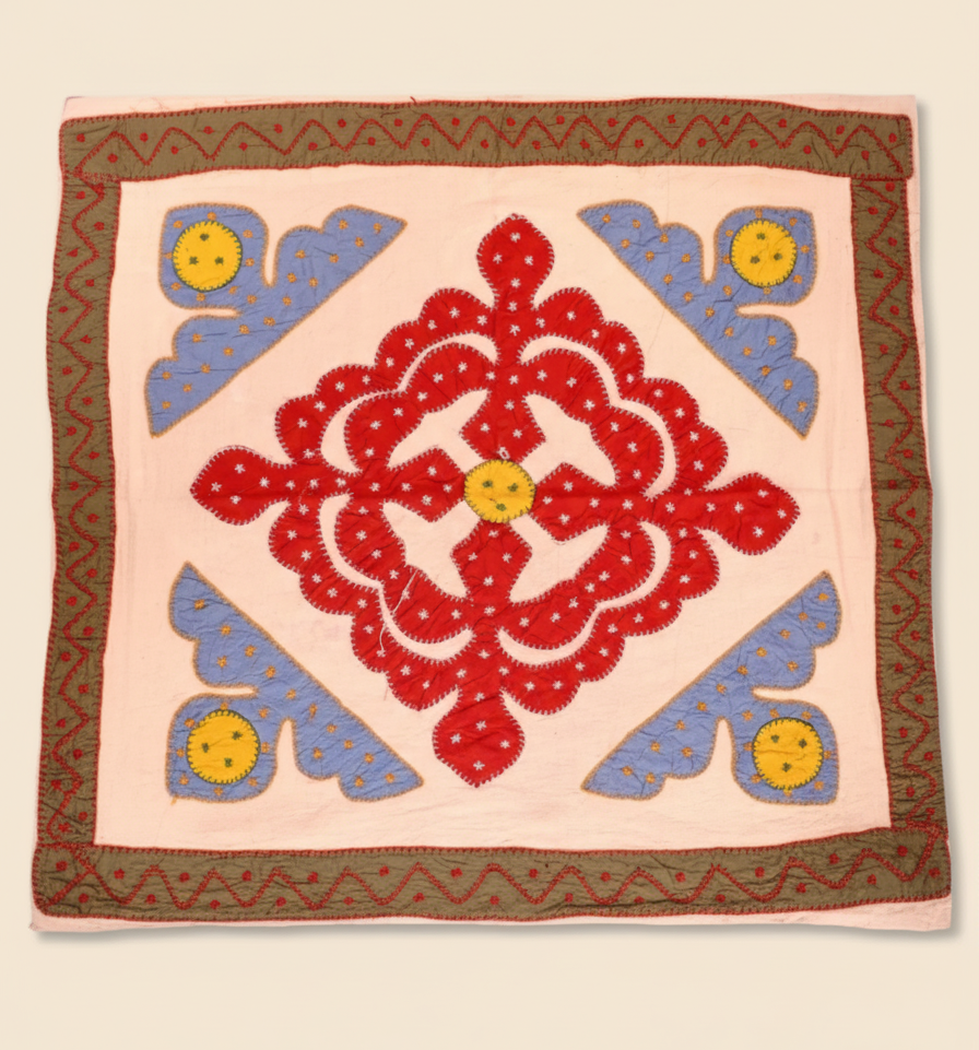 Decorative pink table cover with red floral design and blue shapes