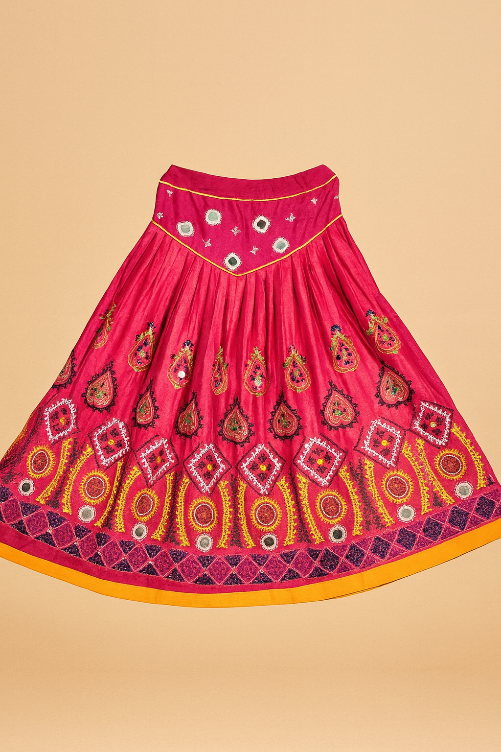 Pink traditional skirt with embroidered intricate patterns on a beige background
