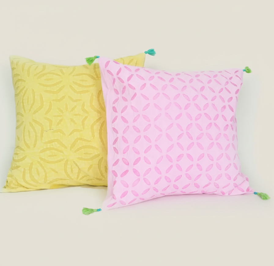 Two patterned pillows, one yellow and one pink, on a light background.