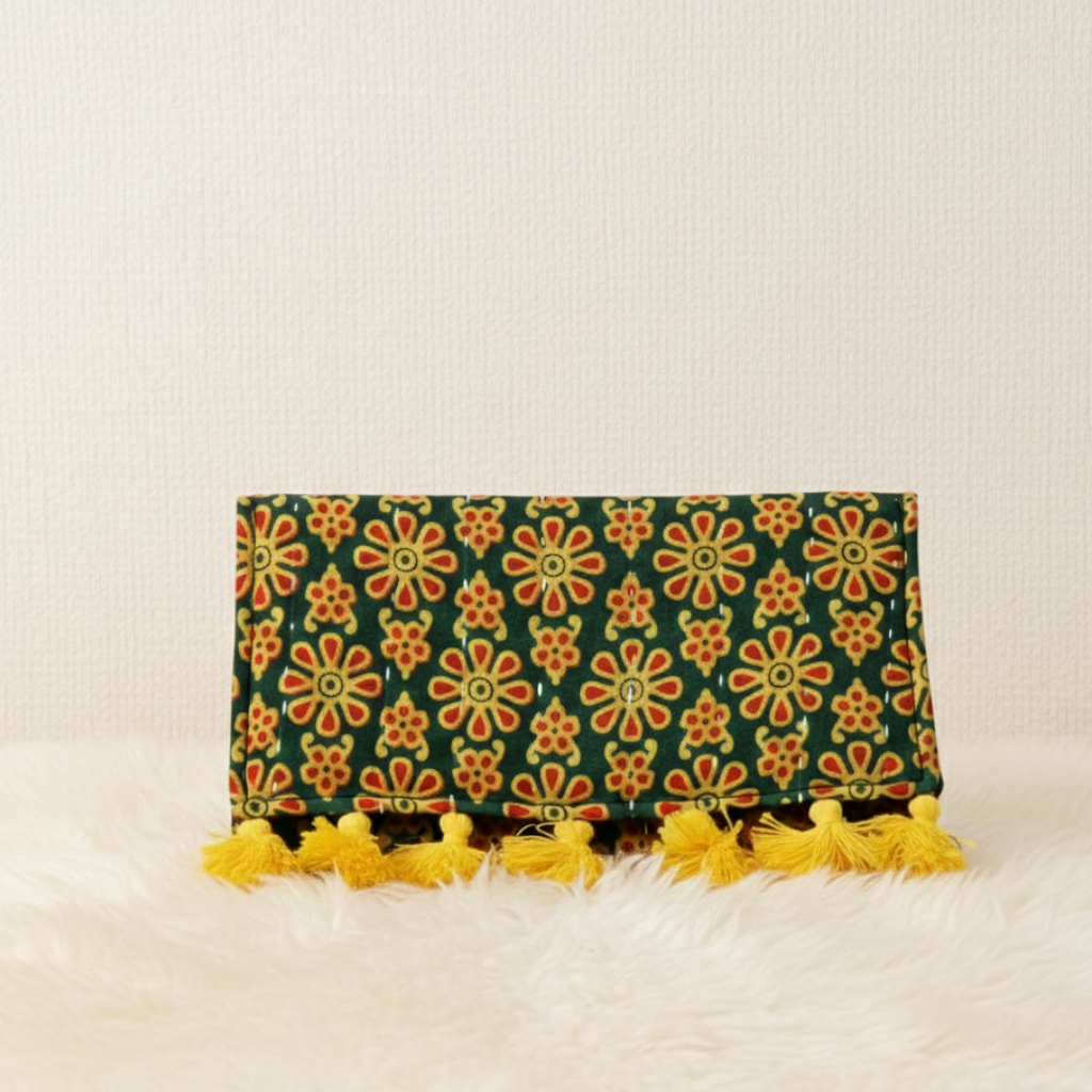 Clutch bag with floral pattern and yellow tassels on a light background
