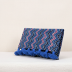 Decorative blue purse with zigzag pattern and tassels on a white background