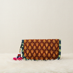 Brown patterned clutch bag with tassels on a textured surface