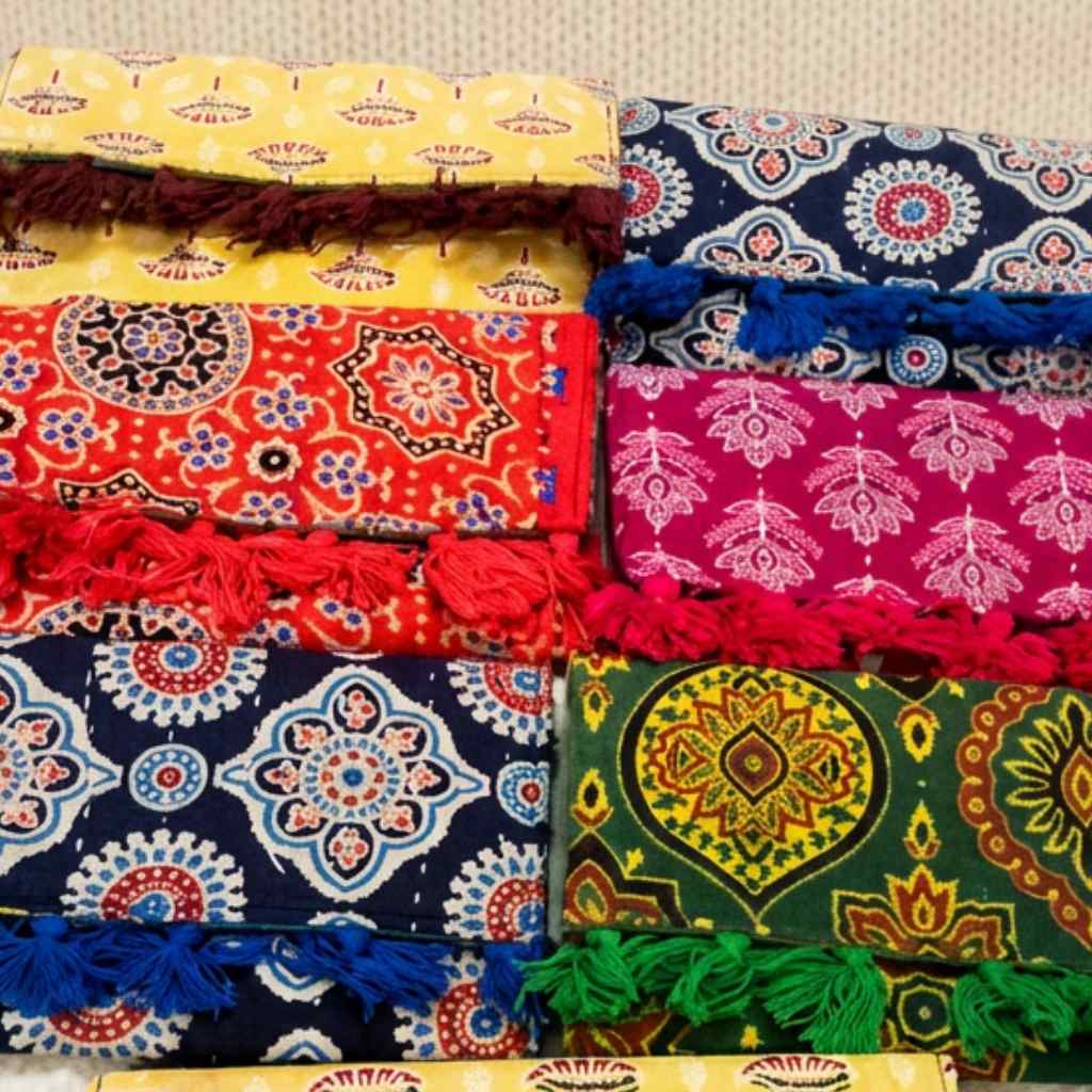 Colorful fabric purses with patterns and fringes on a textured surface