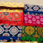 Colorful fabric purses with patterns and fringes on a textured surface