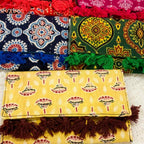 Colorful ajrakh print purse with patterns and tassels on a textured surface