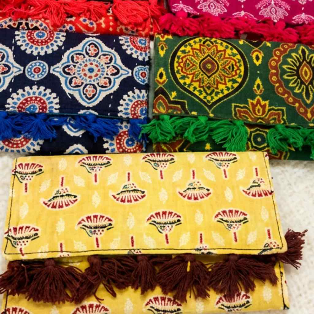 Colorful ajrakh print purse with patterns and tassels on a textured surface
