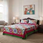 Colorful floral-patterned bedspread on a bed in a bedroom with abstract art on the wall.
