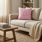 Beige sofa with a pink applique cushion cover and wooden side table in a living room setting.