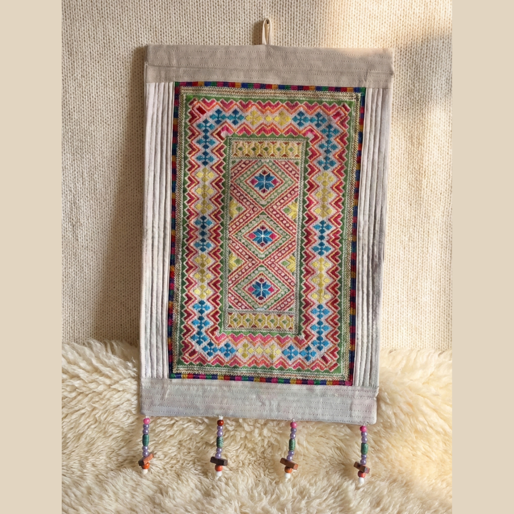 Decorative wall hanging with colorful geometric pattern on a textured beige background
