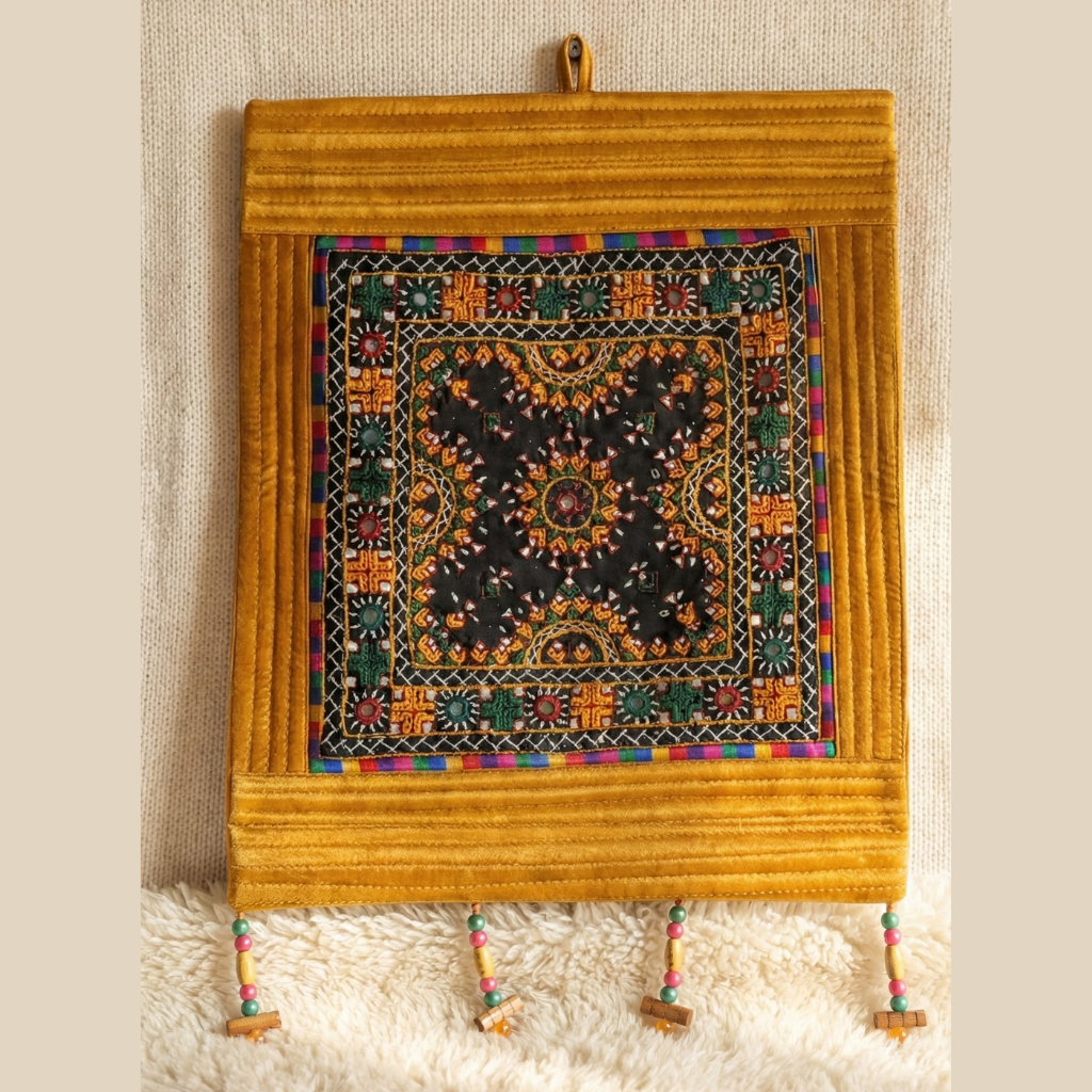 Decorative wall hanging with intricate patterns and colorful accents on a textured surface.