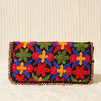 Colorful embroidered clutch bag on a textured beige background