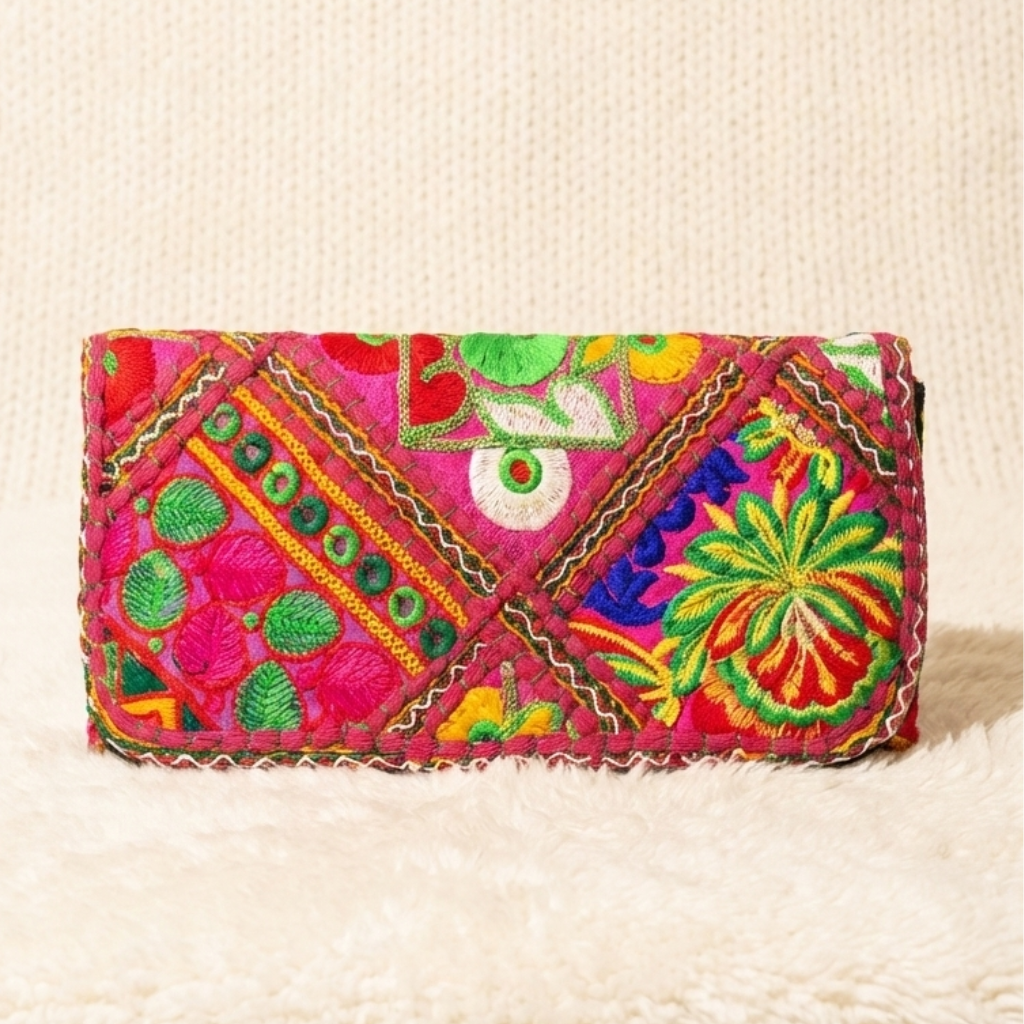 Colorful embroidered clutch bag on a textured beige surface