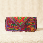 Colorful embroidered clutch bag on a textured beige surface