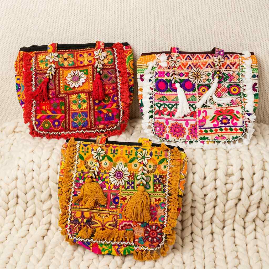 Three colorful embroidered tote bags on a textured surface