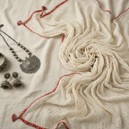 White fabric with red embroidery and jewelry on a light background
