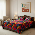 Bedroom with a colorful checkered quilt and pillows on a bed.