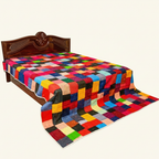 Colorful checkered quilt on a wooden bed with a white background