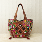 Colorful embroidered handbag with pom-poms on a textured white background