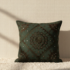 Decorative dark green cushion cover with intricate pattern on a neutral background