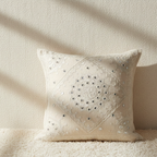 Decorative white cushion cover with intricate embroidery on a textured surface