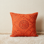 Decorative orange cushion cover with intricate patterns on a neutral background