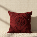 Red decorative cushion cover with intricate patterns on a neutral background