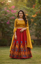 Woman in a yellow top and red skirt with floral patterns standing outdoors.