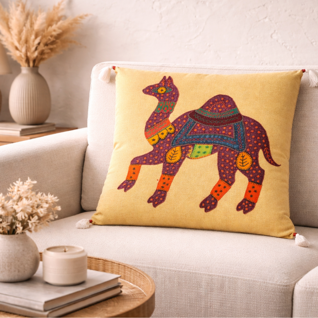 Decorative yellow applique cushion cover with a camel design on a beige sofa