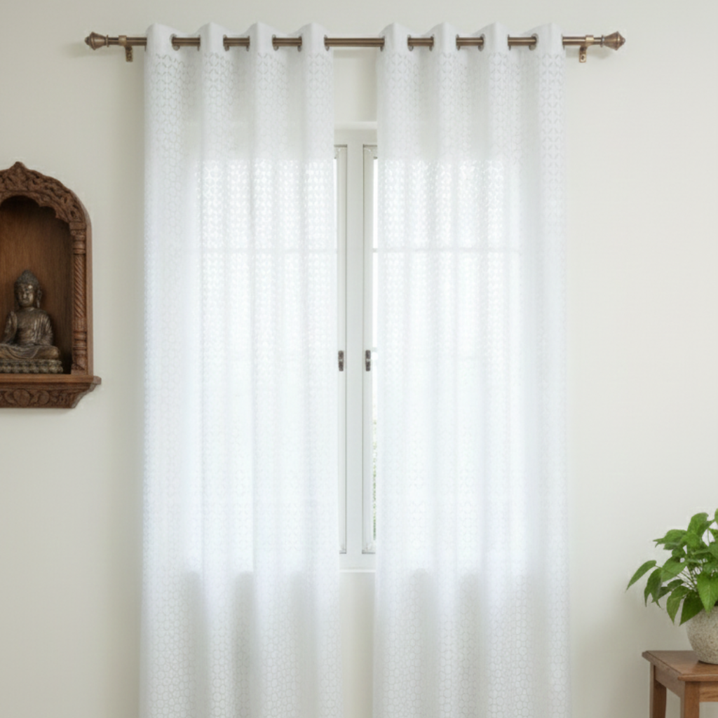 White curtains with grommets in a room with a Buddha statue and plant.