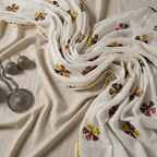 White dupatta fabric with floral embroidery on a beige surface, accompanied by silver jewelry.