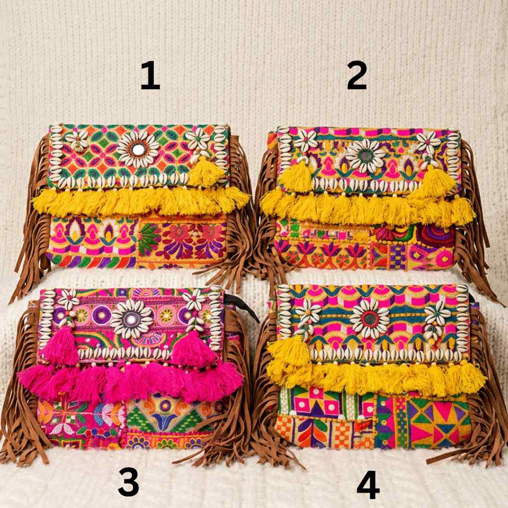 Four colorful banjara laptop handbags with intricate patterns and tassels on a textured beige background.
