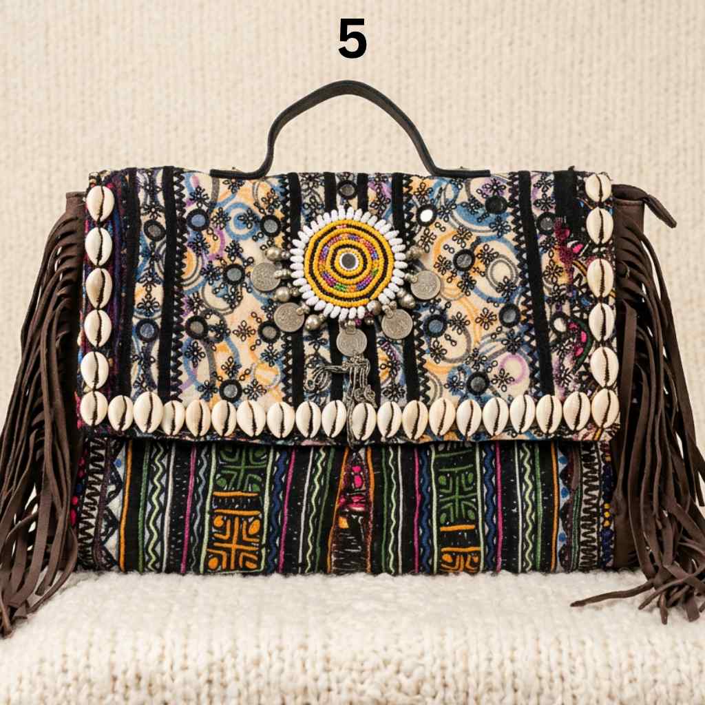 Colorful black banjara laptop bag with patterns and shell embellishments on a textured surface