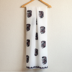 White applique dupatta with black elephant pattern hanging on a wooden hanger against a beige wall.