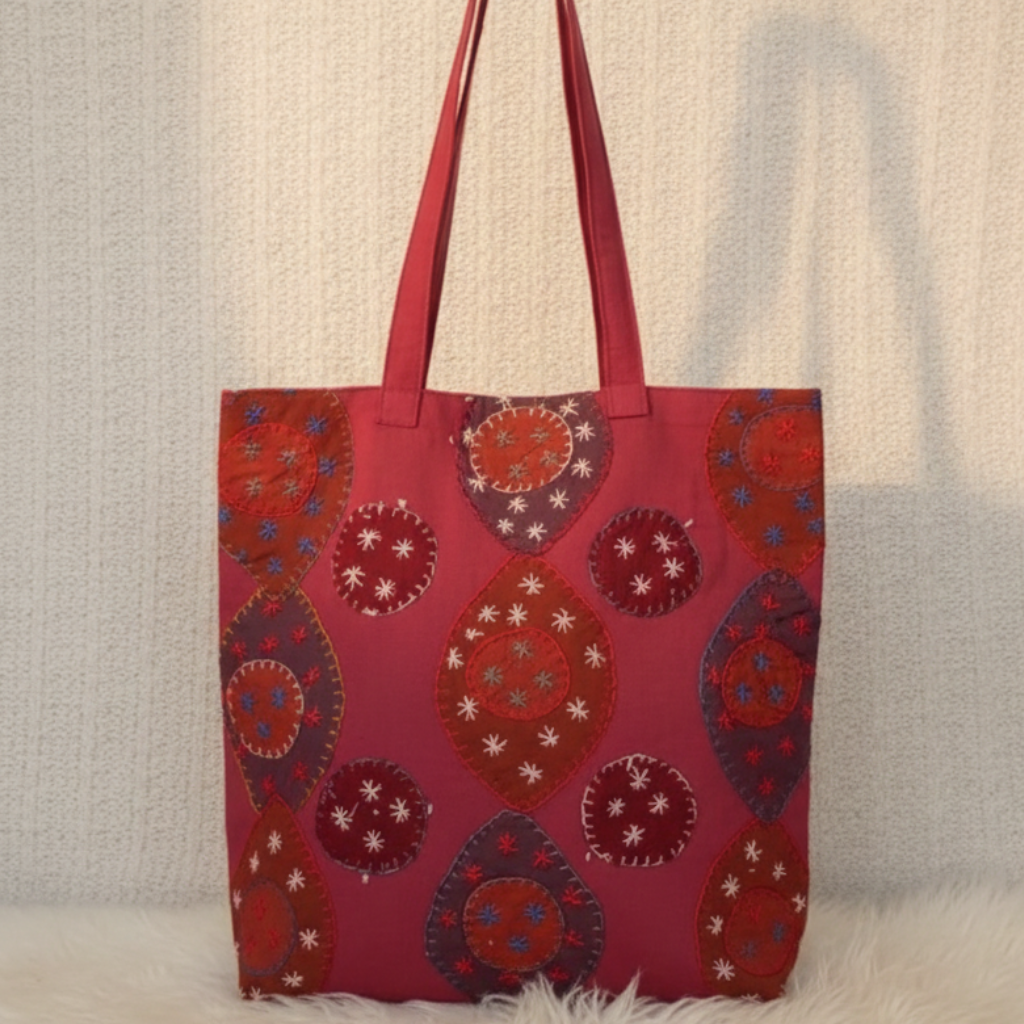 Red tote bag with patterned design on a textured surface