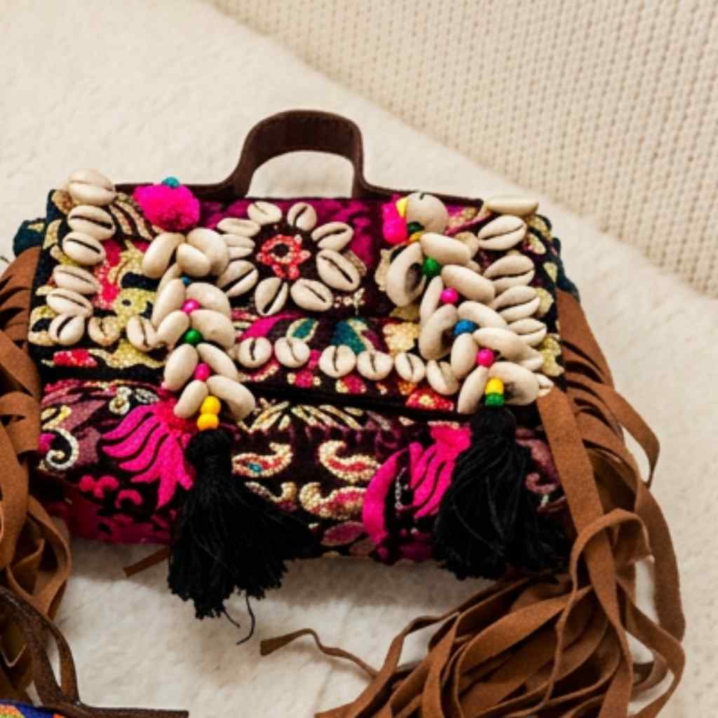 Colorful boho handbag with shell embellishments and tassels on a light background