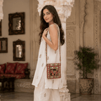 a woman in a white kurta set carrying an elephant design red embroidered sling bag