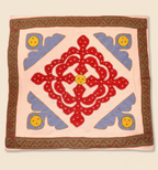 Decorative pink table cover with red floral design and blue shapes 