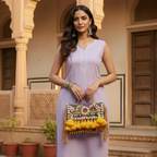 Woman in a lavender dress holding a colorful handbag in front of an architectural background