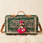 Decorative handbag with pink pom-poms and shell embellishments on a textured surface