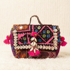 Colorful handbag with intricate patterns and shell decorations on a textured beige background