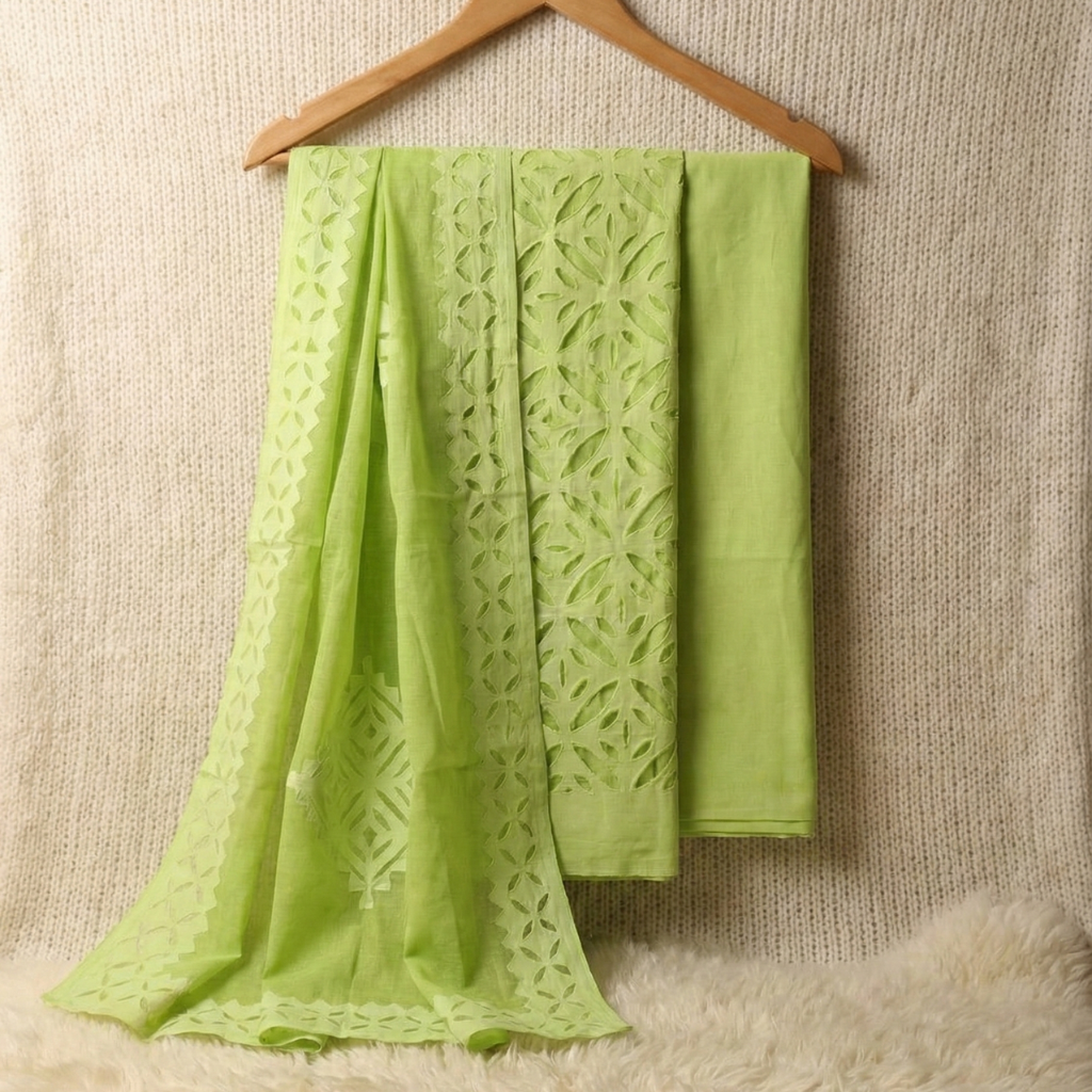 Green fabric with intricate patterns draped over a wooden hanger against a textured beige background.