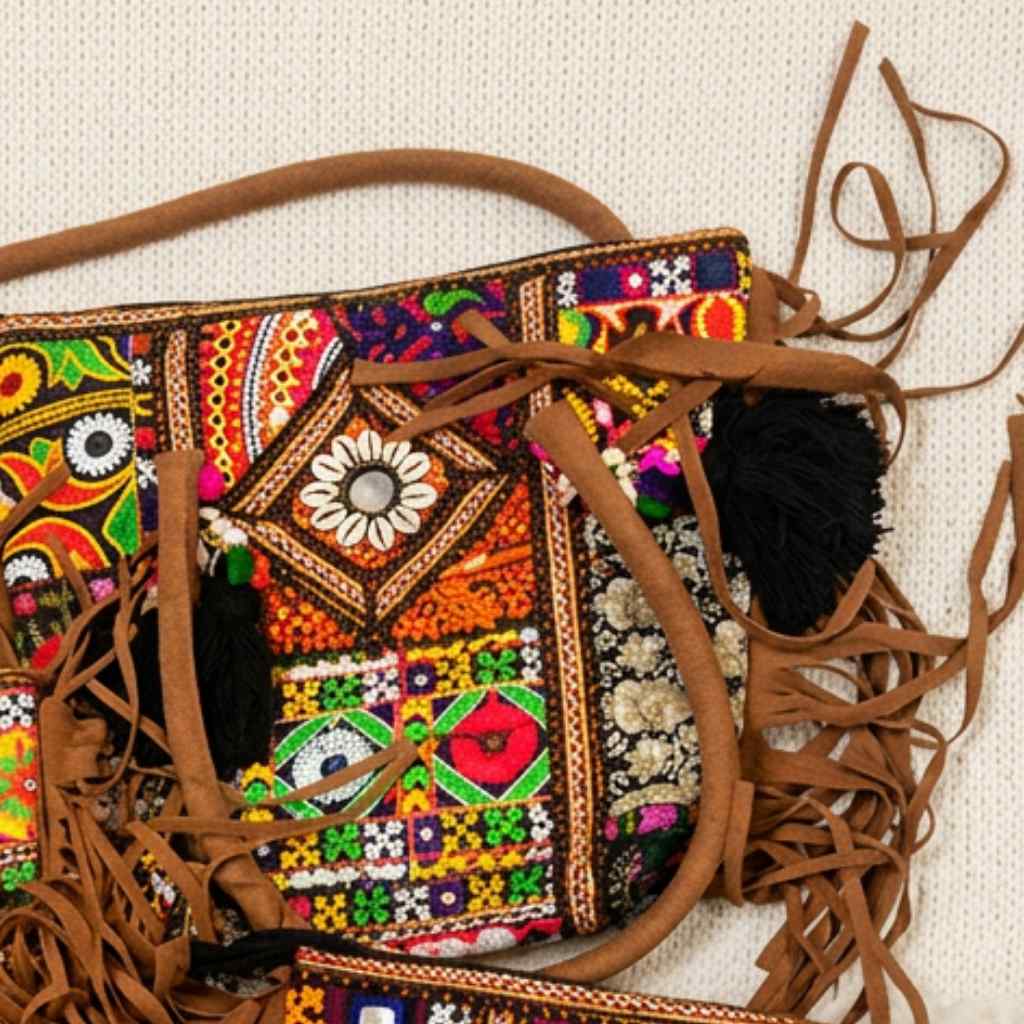 Colorful embroidered banjara tote with brown leather straps on a light background