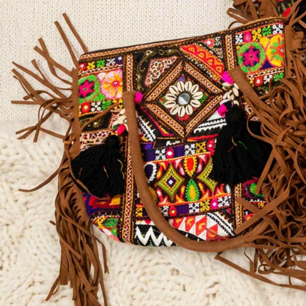 Colorful embroidered tote bag with tassels on a textured surface