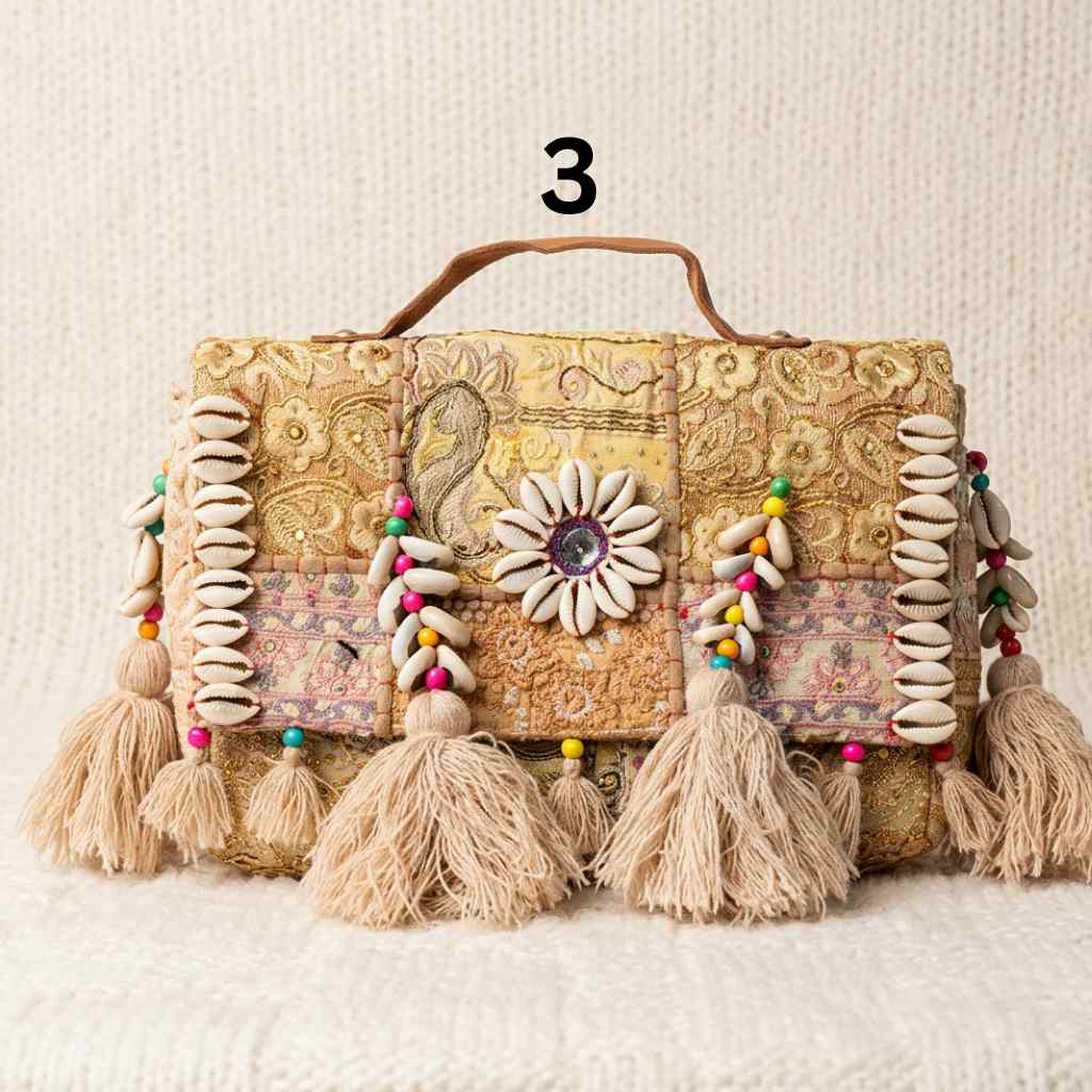 Decorative beige banjara handbag with tassels and shell embellishments on a textured surface