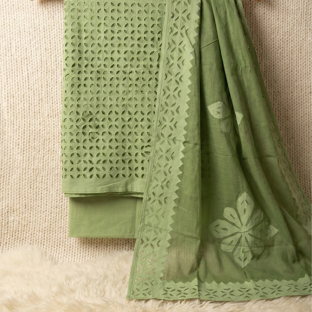 Green fabric with intricate cut-out patterns on a textured surface