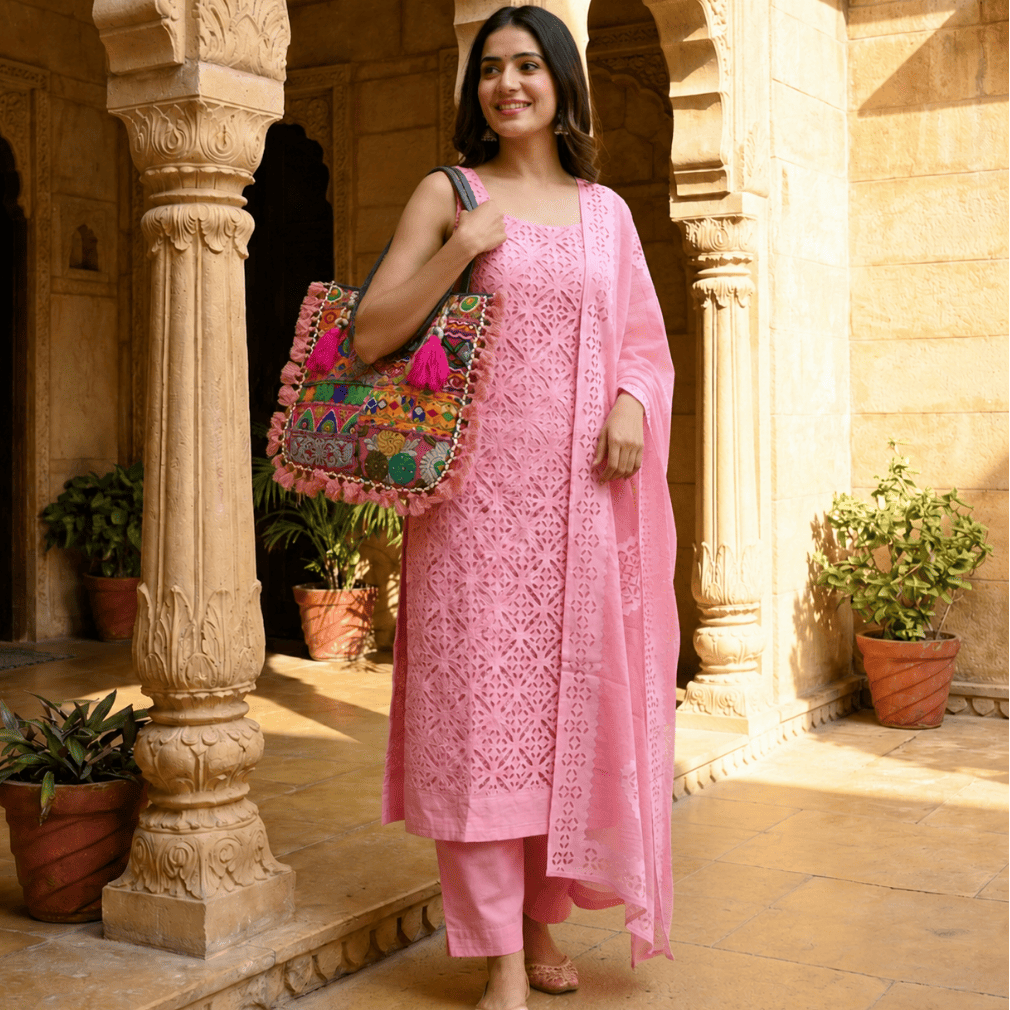 a woman in a pink applique suit set carrying a banjara bag with pink tassel detailing