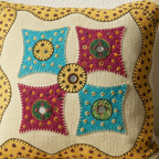 Decorative applique cushion cover with colorful embroidered patterns on a beige background