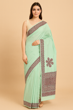 Woman wearing a light green applique work saree with  floral patterns 