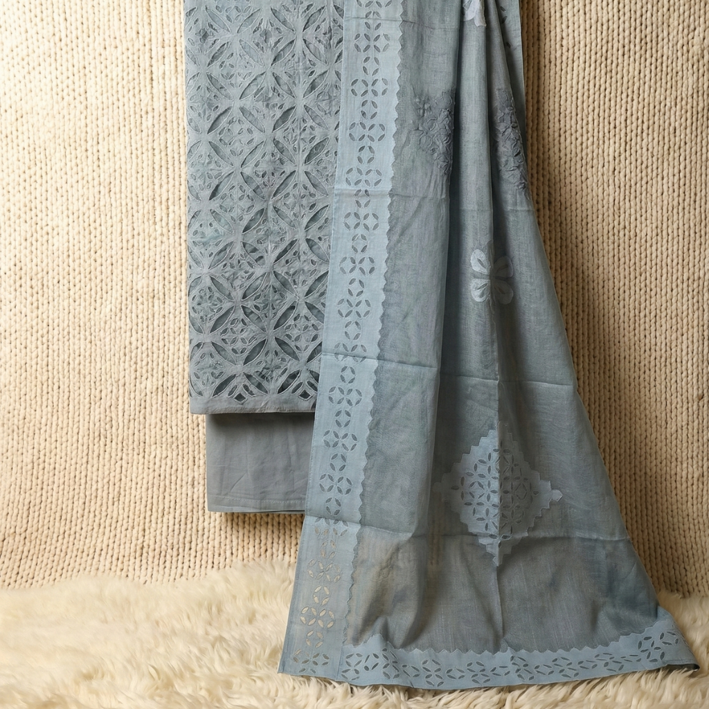 Gray fabric with intricate lace patterns draped over a textured beige surface