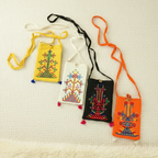 Four embroidered pouches in yellow, white, black, and orange on a textured beige background.